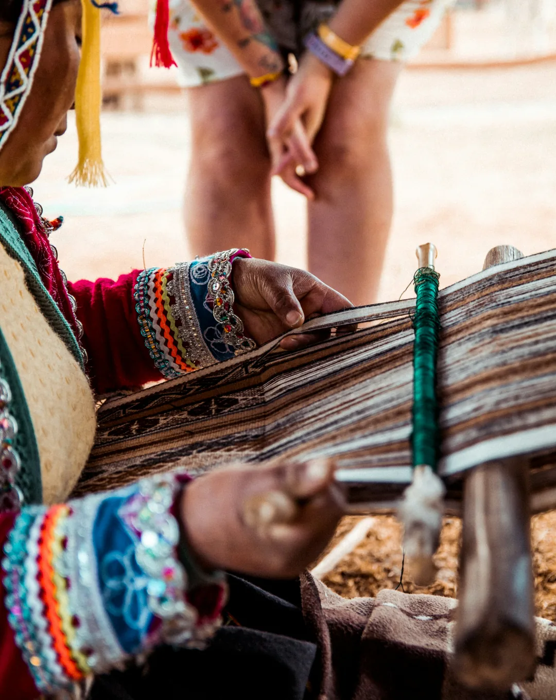 Hands of an Andean weaver with woven textiles