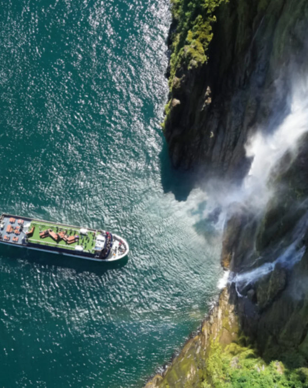 Cruise boat beside a waterfall in Milford Sound